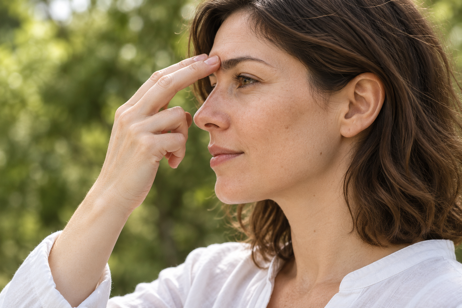 Woman gently touching her inner eyebrow with two fingertips while practising tapping